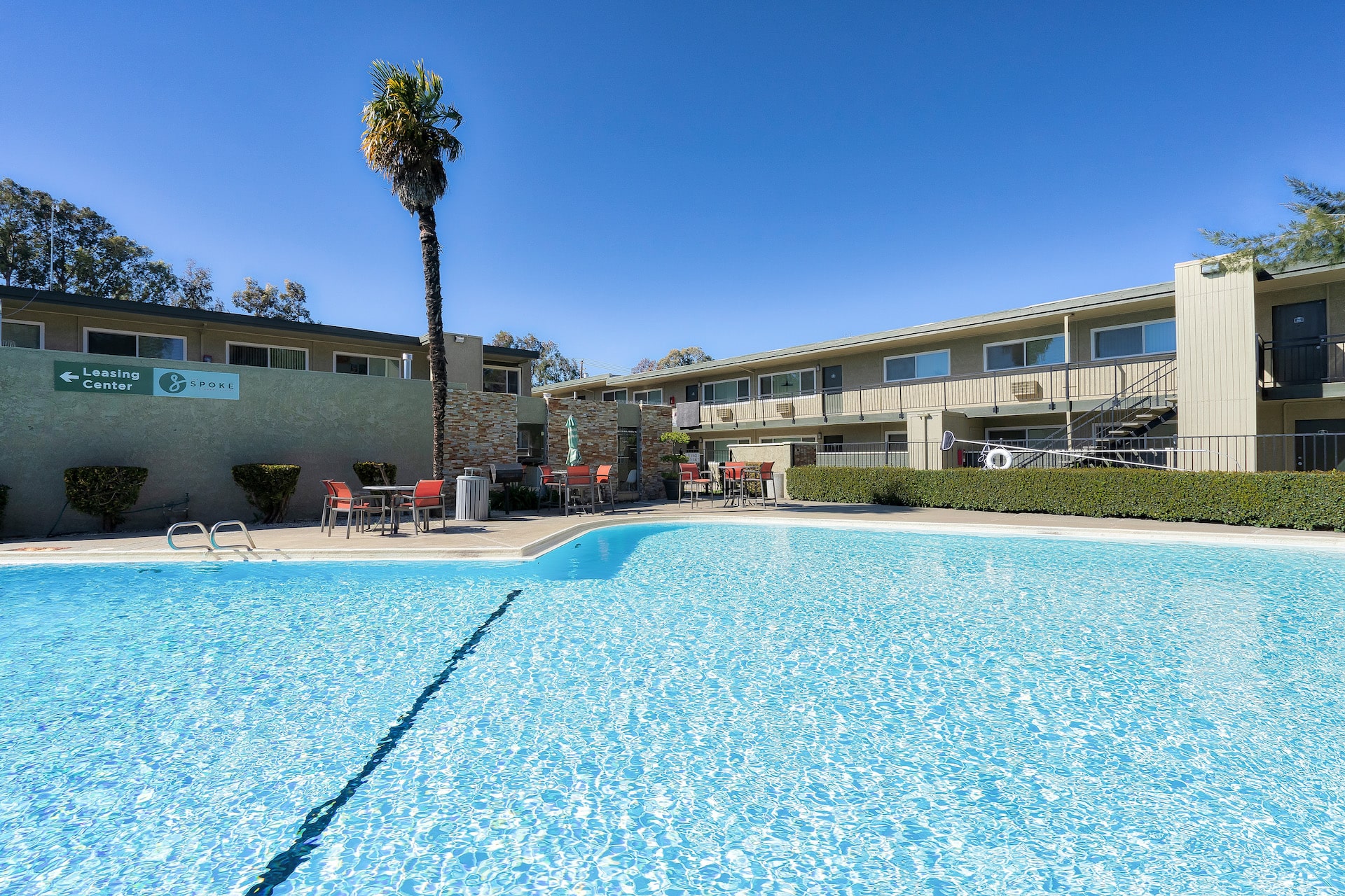 swimming pool with a clubhouse in the background at the spoke apartments