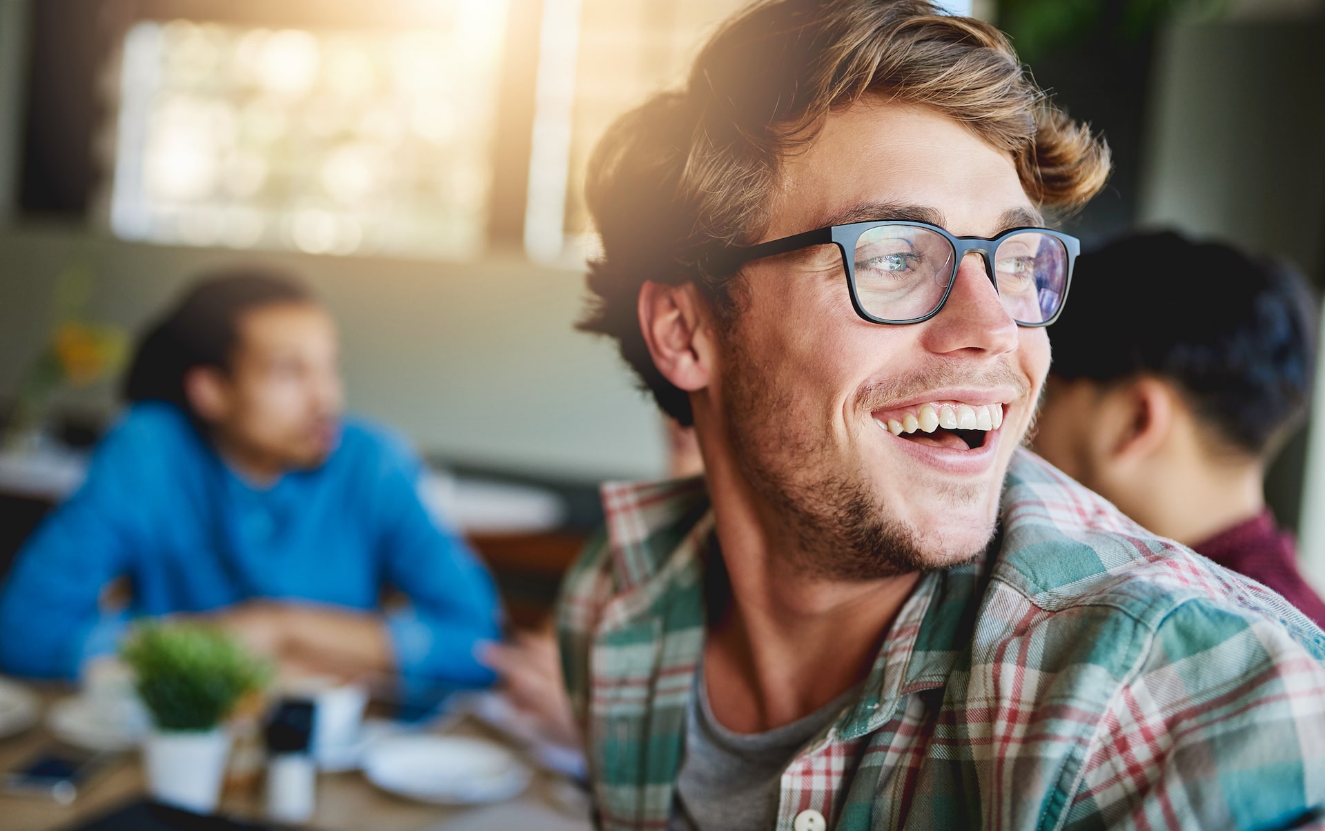Person with glasses looking back and laughing.