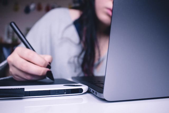 woman using a drawing pad while on her laptop